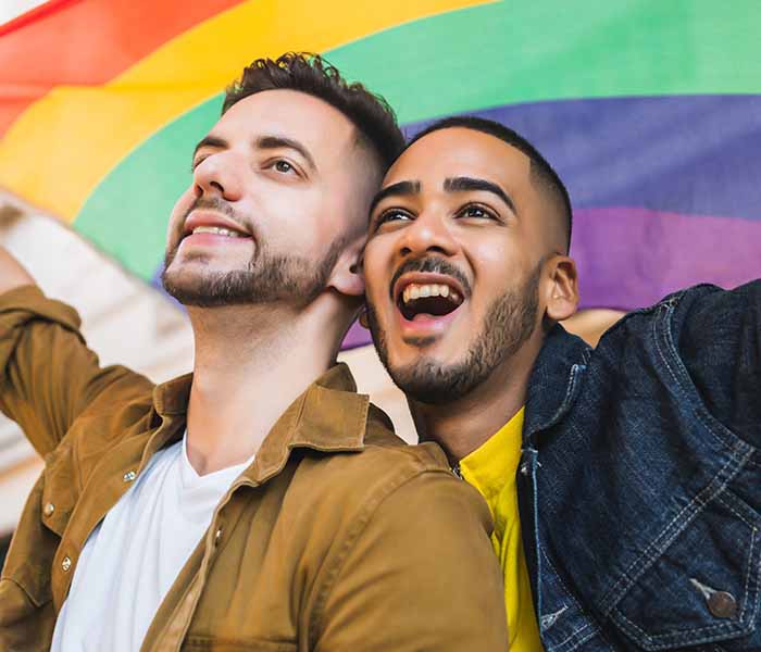 2 men as a couple holding the rainbow flag