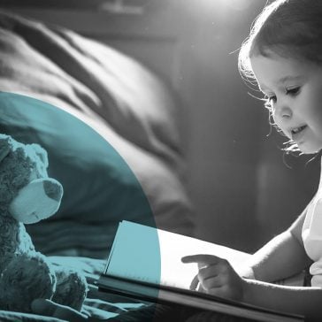 Little girl reading a story to a teddy bear